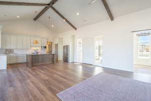Unfurnished living room with high vaulted ceiling, beamed ceiling, dark wood-style flooring, and recessed lighting