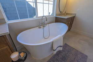 Bathroom with vanity, light tile patterned floors, and a freestanding tub