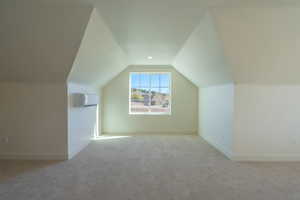 Bonus room with light carpet, lofted ceiling, and a wall mounted air conditioner