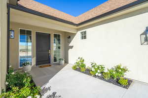 Property entrance with roof with shingles and stucco siding
