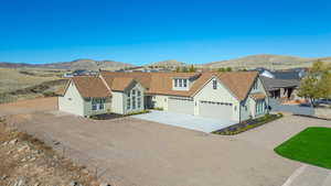View of front of house featuring a mountain view, concrete driveway, stucco siding, and a shingled roof