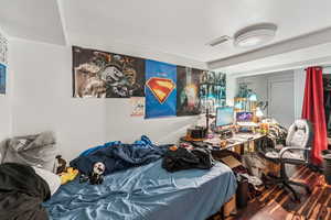 Bedroom with wood finished floors and an office area