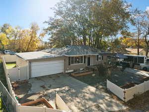 Ranch-style house featuring a vegetable garden, a fenced front yard, a gate, driveway, and a garage