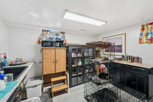 Kitchen with dark cabinetry, light wood finished floors, black appliances, and wood counters