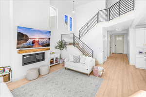 Living room with light wood finished floors, a high ceiling, and stairs