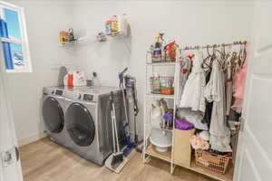 Laundry area with light wood-style flooring and washing machine and dryer