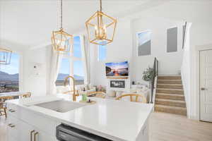 Kitchen with white cabinets, light wood-type flooring, and hanging light fixtures
