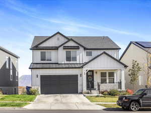Modern farmhouse with board and batten siding, a porch, roof with shingles, and an attached garage