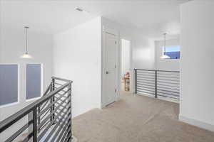 Corridor featuring an upstairs landing and light carpet