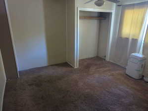 Unfurnished bedroom with carpet, a closet, and a ceiling fan