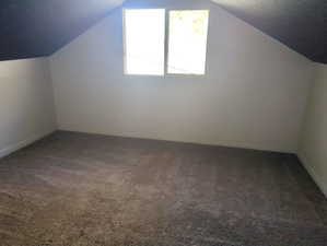 Additional living space with carpet flooring and lofted ceiling