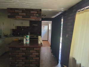 Kitchen with freestanding refrigerator, light countertops, white cabinets, and backsplash