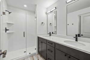 Full bath with double vanity, a shower stall, a textured ceiling, and recessed lighting
