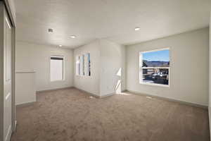 Unfurnished room with light colored carpet, a textured ceiling, and recessed lighting