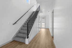 Stairway featuring wood finished floors and recessed lighting