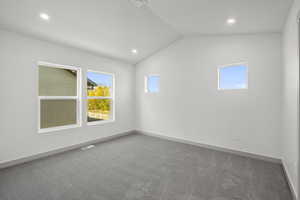 Empty room featuring light colored carpet, vaulted ceiling, and recessed lighting