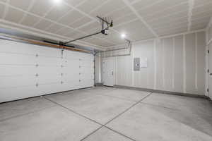 Garage featuring electric panel and a garage door opener