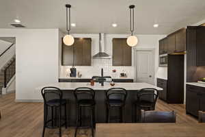 Kitchen with a kitchen island with sink, pendant lighting, dark wood finish cabinets, and a kitchen breakfast bar