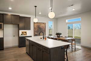 Kitchen with dark wood finish cabinetry, a breakfast bar, hanging light fixtures, and dark wood-style floors
