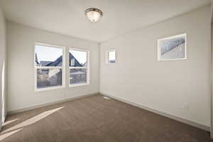 Empty room featuring dark carpet and baseboards