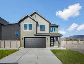 View of front of home with a mountain view, an attached garage, driveway, stucco siding, and covered porch