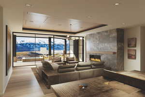 Living room with a fireplace, a raised ceiling, a wall of windows, a mountain view, and recessed lighting