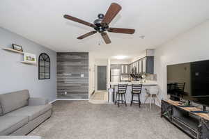 Living area featuring ceiling fan, light carpet, and a textured ceiling