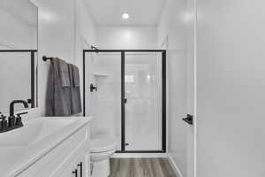 Bathroom with vanity, a shower stall, and light wood-style flooring