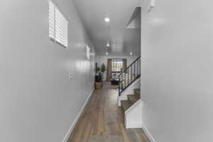 Hall with dark wood-style floors, stairs, and recessed lighting