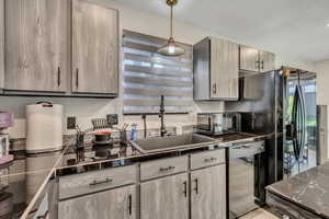Kitchen with hanging light fixtures and black appliances