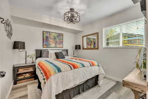 Bedroom with wood finished floors and a chandelier