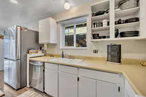 Kitchen featuring white cabinets, light countertops, stainless steel appliances, and open shelves