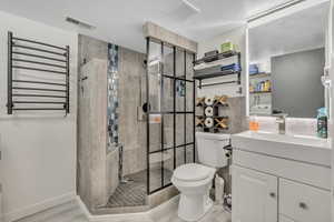 Bathroom with radiator heating unit, a towel warming rack, vanity, and a stall shower