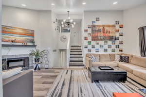 Living room featuring wood finished floors, recessed lighting, a tile fireplace, a chandelier, and stairway