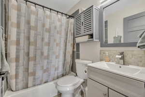 Full bath with backsplash, vanity, and shower / bath combo