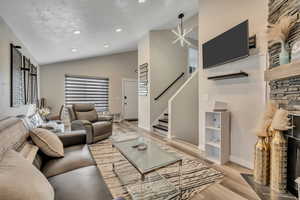 Living room featuring stairs, light wood finished floors, recessed lighting, and high vaulted ceiling