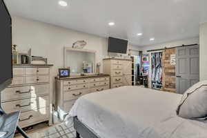 Bedroom with a barn door, recessed lighting, and a spacious closet