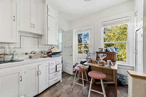 Kitchen with tile counters, white cabinetry, and backsplash