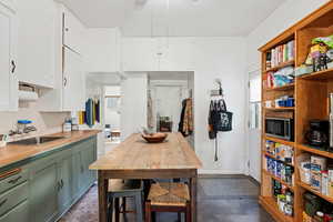 Kitchen with green cabinets, white cabinets, tasteful backsplash, stainless steel microwave, and wood counters