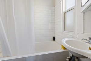 Full bath with healthy amount of natural light and tiled shower / bath combo
