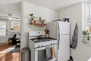Kitchen with healthy amount of natural light, white appliances, wood finished floors, and open shelves