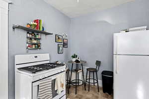 Kitchen with white appliances, open shelves, and a textured wall