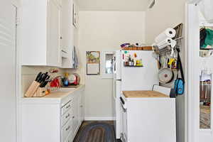 Kitchen featuring white cabinets, freestanding refrigerator, washer / dryer, tile countertops, and decorative backsplash