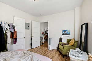 Bedroom with light wood-style floors, electric panel, and a desk