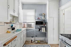 Kitchen featuring white cabinets, tile countertops, open shelves, white range with gas stovetop, and light tile patterned floors