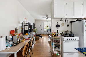 Kitchen featuring white appliances, light wood-style floors, white cabinetry, and ceiling fan