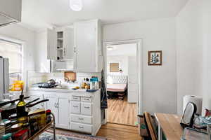 Kitchen featuring white cabinets, backsplash, light wood finished floors, and open shelves