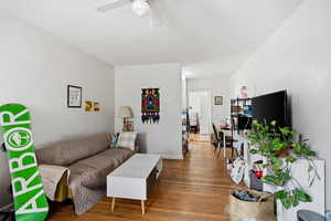Living area featuring wood finished floors, a desk, and a ceiling fan