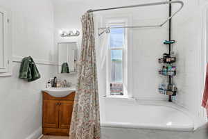 Full bathroom with shower / tub combo, vanity, and a textured wall