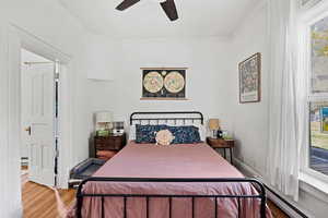 Bedroom with a baseboard radiator, wood finished floors, and ceiling fan